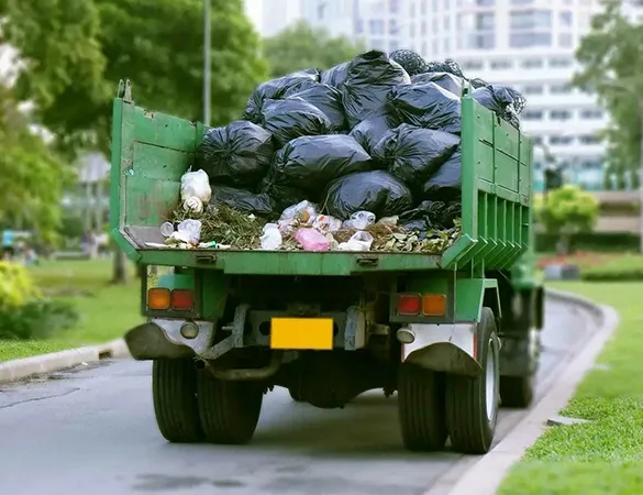 Green hauling truck transporting bags of debris in Wilton Manors, FL, representing affordable furniture and debris removal services.
