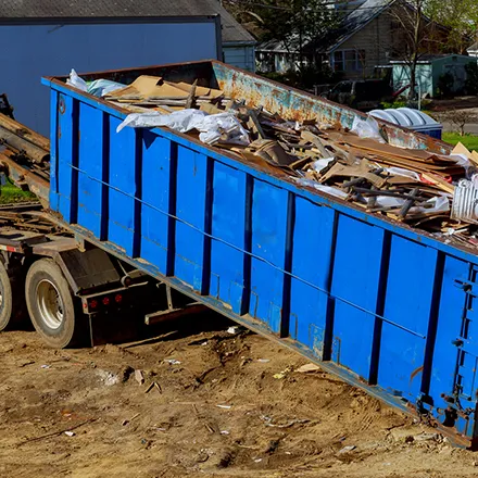 Blue dump trailer filled with debris and junk for removal, showcasing reliable junk removal services and efficient disposal solutions.