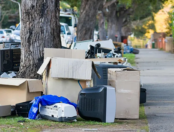 Piled junk including cardboard boxes and electronic waste on the street in Fort Lauderdale, FL, highlighting the need for reliable junk hauling services.